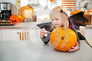 Halloween dressed girl creating big pumpkin Jack-O-Lantern