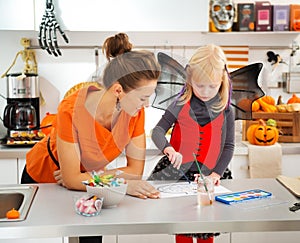 Halloween dressed girl and mother drawing Jack-O-Lantern