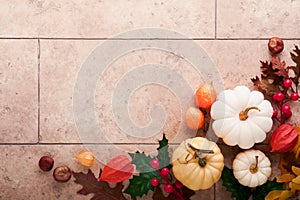 Halloween festive autumn background. Autumn decor from pumpkins, berries, maple leaves and chestnuts on old rustic stone tiles