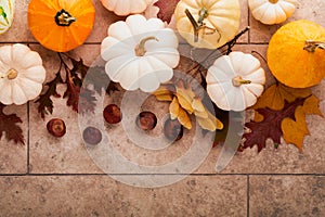 Halloween festive autumn background. Autumn decor from pumpkins, berries, maple leaves and chestnuts on old rustic stone tiles