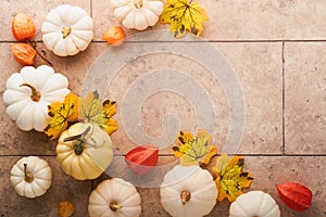 Halloween festive autumn background. Autumn decor from pumpkins, berries, maple leaves and chestnuts on old rustic stone tiles bac