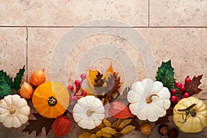Halloween festive autumn background. Autumn decor from pumpkins, berries, maple leaves and chestnuts on old rustic stone tiles bac