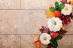 Halloween festive autumn background. Autumn decor from pumpkins, berries, maple leaves and chestnuts on old rustic stone tiles bac