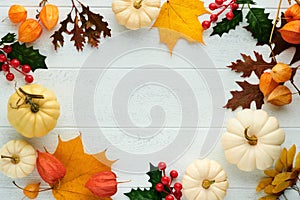 Halloween festive autumn background. Autumn decor from pumpkins, berries, maple leaves and chestnuts on old rustic white wooden
