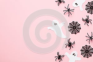 Halloween flat lay composition. Top view Halloween decorations, spiders, webs, ghosts on pastel pink table