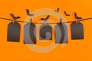 Halloween flock bats and black blank labels tomb hanging on clothespins, on orange background, mock up.