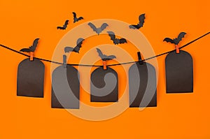 Halloween flock bats and black blank labels tomb hanging on clothespins, on orange background, mock up.