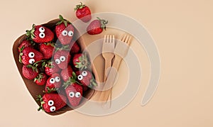 Halloween food. Scared strawberries with eyes in a food container with a fork on a light background. Creepy food. Halloween