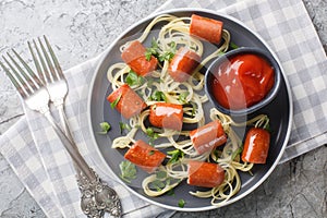 Halloween food spiders funny spaghetti with hot dog and ketchup close-up in a plate. Horizontal top view