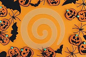 Halloween frame flat lay. Modern pumpkins jack o lantern, spiders, bats frame on orange background with space for text. Season`s