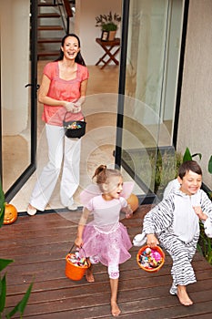 Halloween is about fun. two happy kids leaving a house on Halloween with buckets of treats.