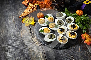 Halloween funny idea for party food. Halloween creative set stuffed eggs on a wooden table. Copy space.