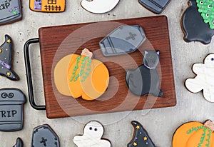 Halloween gingerbreads, pumpkin, tombstone, black cat on a board over wooden table