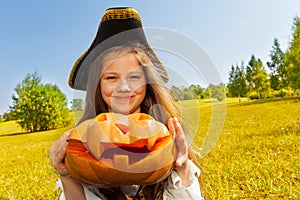 Halloween girl in costume of pirate holds pumpkin