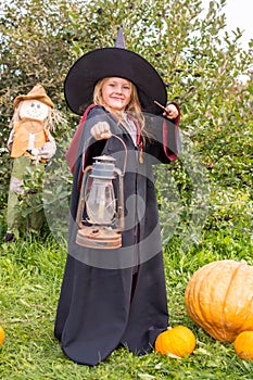 Halloween. A girl in a robe and hat. A little sorceress in the costume.