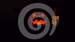 Halloween glowing pumpkins with black background. Orange glow light inside of carved pumpkin heads. Dark smile faces.