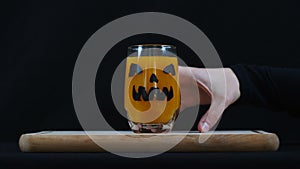 Halloween. Hand steals a glass of orange juice.
