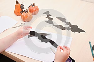 Halloween handmade decor. Child makes paper bat