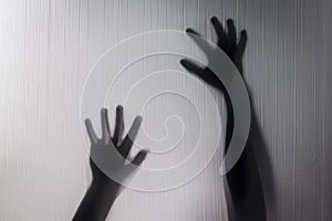 Halloween hands behind transparent glass blur background as silhouette