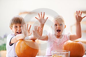 Halloween, hands and carving a pumpkin with children at a home table for fun and bonding. Boy and girl or young kids as