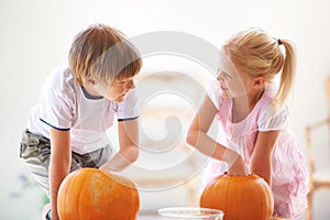 Halloween, happy and carving a pumpkin with children at a home table for fun and bonding. Boy and girl or young kids as