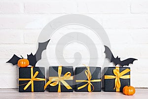 Halloween holiday background with gifts and bats against a white brick wall