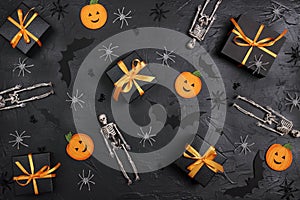 Halloween holiday background with gifts and decorations on black backdrop