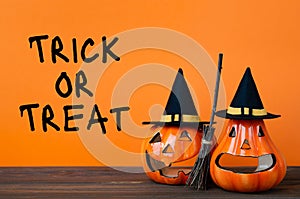 Halloween holiday background with jack lanterns pumpkin, broom and witch hat on wooden table