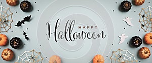 Halloween holiday background with party decorations from pumpkins, bats, ghosts, spider webs on blue top view. Greeting card