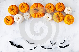 Halloween holiday background with party decorations of pumpkins and bats on white table top view. Happy halloween greeting card