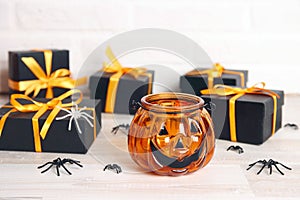 Halloween holiday background with pumpkin Jack lantern candlestick and gifts on a table
