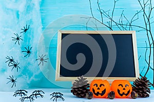 Halloween holiday background with spider, webs, blackboard and jack lantern on blue wooden table with copy space for text. Flat