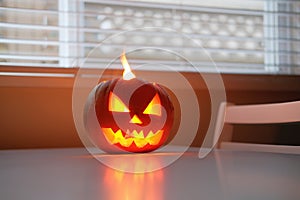 Halloween holiday celebration symbol, pumpkin on kitchen table glowing