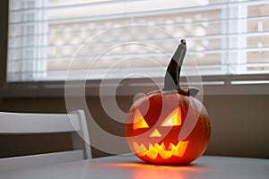 Halloween holiday celebration symbol, pumpkin on kitchen table glowing