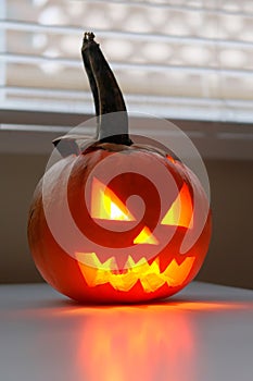 Halloween holiday celebration symbol, pumpkin on kitchen table glowing
