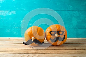 Halloween holiday concept with cute funny pumpkin decor on wooden table over blue background