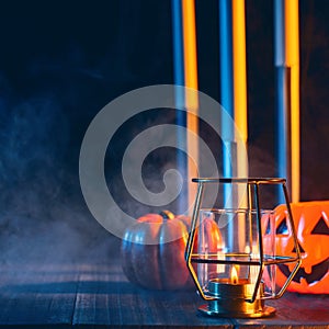 Halloween holiday concept design of pumpkin, candle, spooky decorations with blue tone smoke around on a dark wooden table, close