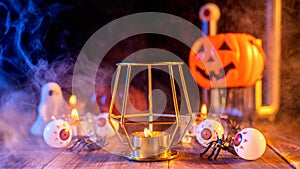 Halloween holiday concept design of pumpkin, candle, spooky decorations with blue tone smoke around on a dark wooden table, close