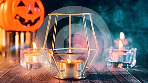 Halloween holiday concept design of pumpkin, candle, spooky decorations with green tone smoke around on a dark wooden table, close