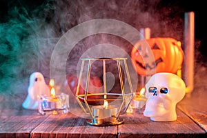 Halloween holiday concept design of pumpkin, candle, spooky decorations with green tone smoke around on a dark wooden table, close