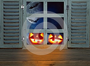 Halloween holiday concept. Empty rustic table in front of haunted night sky background and old window. Ready for product display m