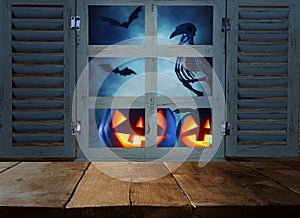 Halloween holiday concept. Empty rustic table in front of haunted night sky background and old window. Ready for product display m