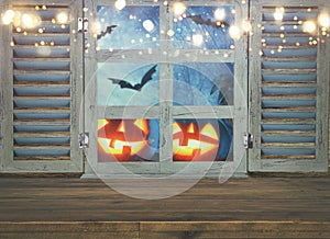 Halloween holiday concept. Empty rustic table in front of haunted night sky background and old window. Ready for product display m