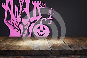 Halloween holiday concept. Empty rustic table in front of haunted witch house over black background. Ready for product display mon