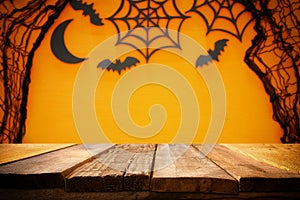 Halloween holiday concept. Empty rustic table in front of spider web and bats background