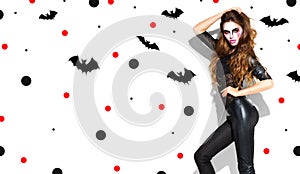 Halloween. Holiday party girl. Beautiful young woman with bright vampire makeup and long hair posing in witches costume