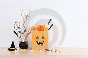 Halloween holoday. witcher cauldron and hat, broom, bare trees, treats and present bag over wooden table