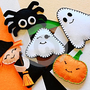 Halloween home decor toys. Felt witch with broom, pumpkin head, two ghosts, spider. Halloween crafts on colored felt sheets photo