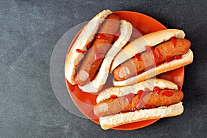 Halloween hot dog fingers on an orange plate over slate