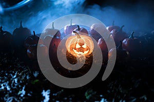 halloween jack-o-lantern on autumn leaves. Scary Halloween Pumpkin looking through the smoke. Glowing